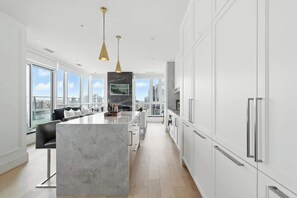 A modern kitchen with a marble island, white cabinetry, and pendant lighting. - 2BR Entertainment District Hub | Balcony & Parking | Parking Available (Toronto)
