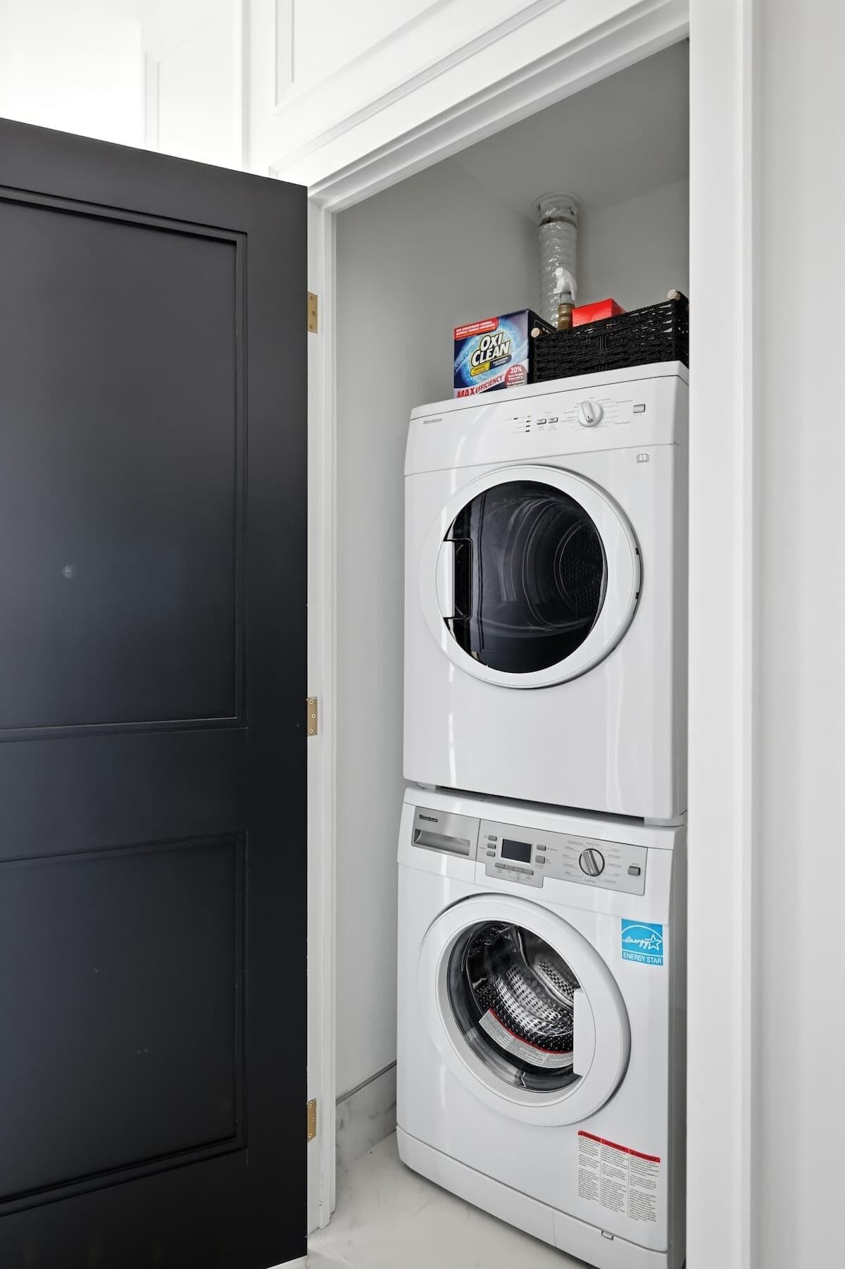 A compact, two-door laundry room with a black door and a white interior.
