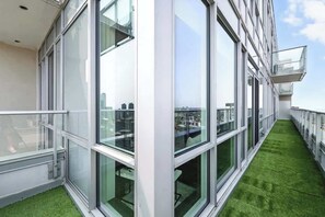 A modern building with large windows and a green artificial grass pathway. - 2BR Entertainment District Hub | Balcony & Parking | Parking Available (Toronto)