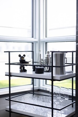Ein Eckregal mit einer Mickey Mouse-Figur, einer silbernen Karaffe und gestapelten Untersetzern.