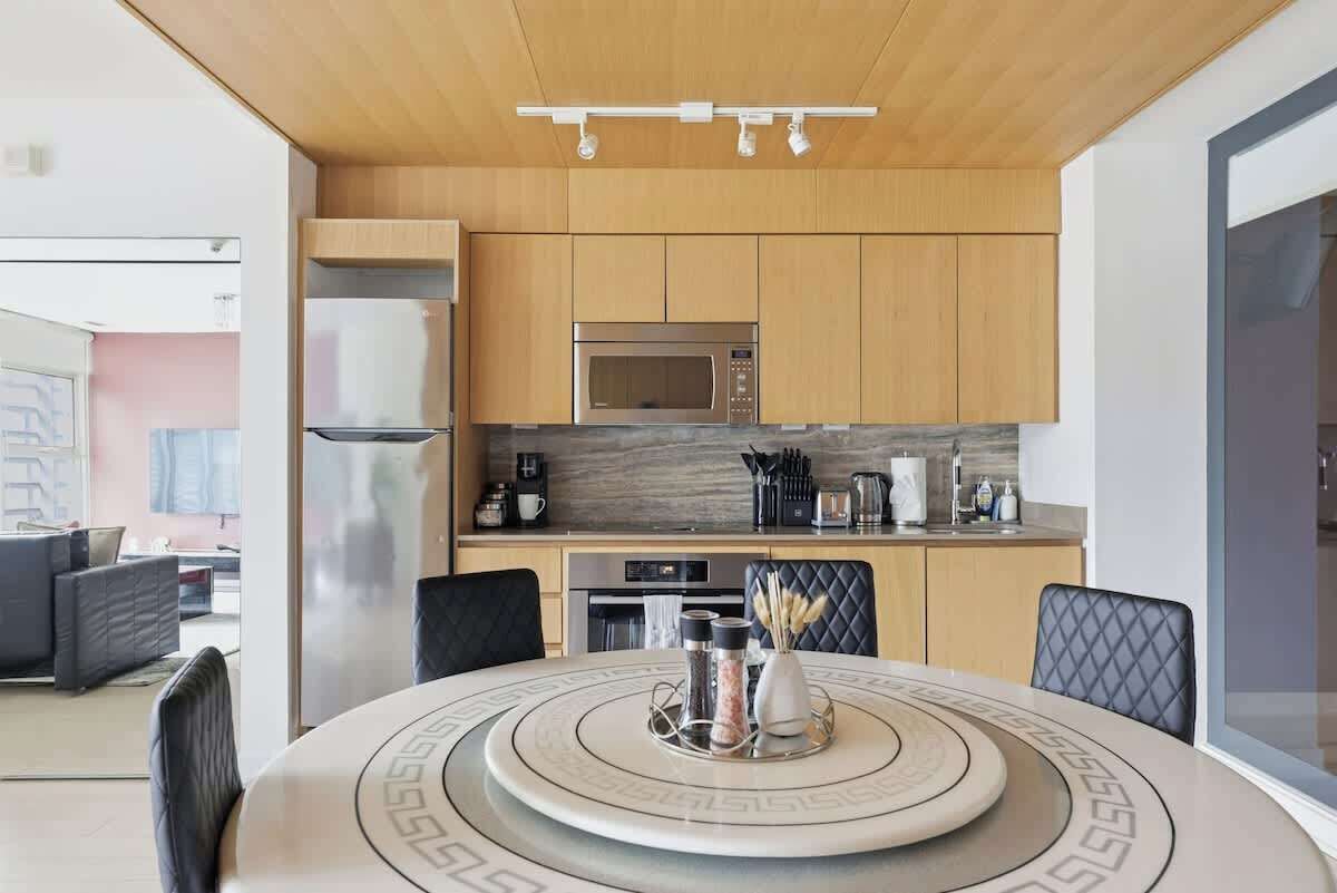 A modern kitchen with a central island, built-in appliances, and a dining area with a round table.