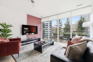 A modern living room with a flat-screen TV, a red sofa, a black sofa, and a glass coffee table.