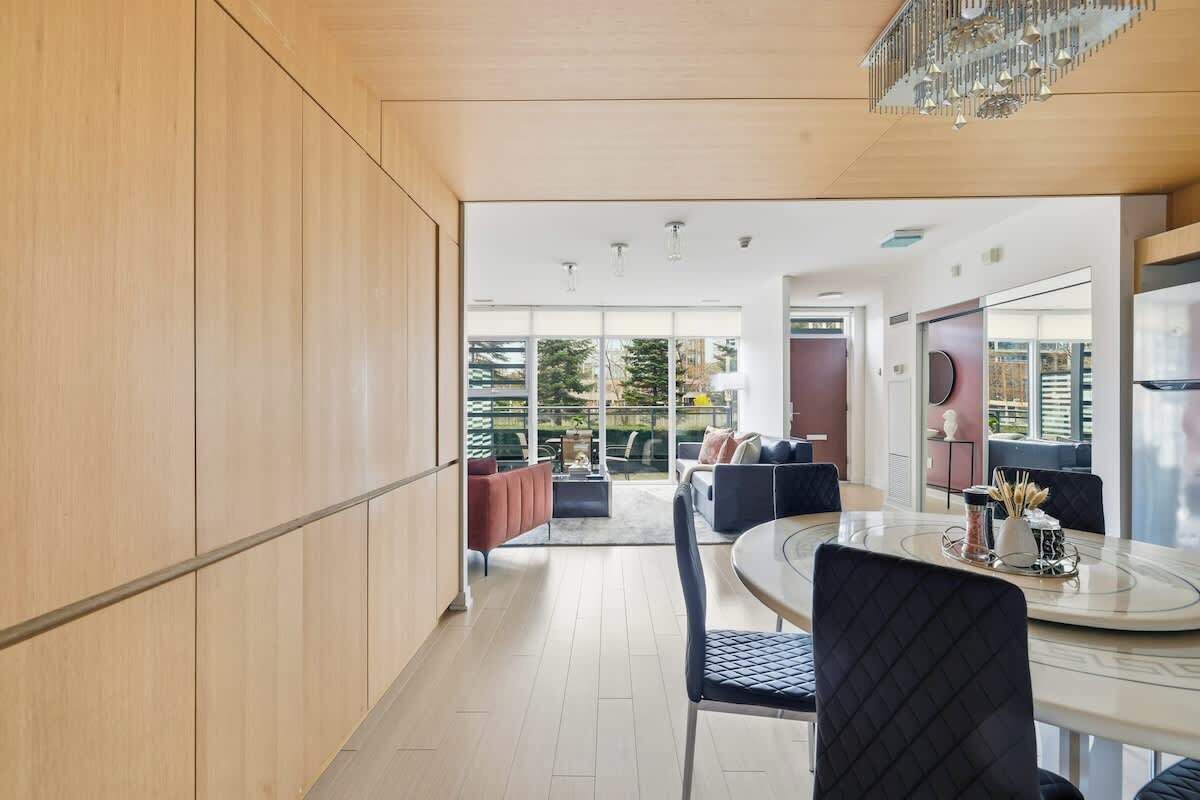 A modern kitchen with a dining area, large windows, and a view of the outdoors.