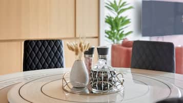 Une table ronde avec un plateau en marbre blanc, un vase blanc contenant des fleurs séchées et deux salières et poivrières noires.