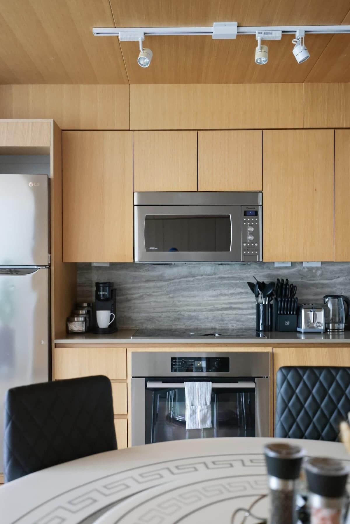 A modern kitchen with wooden cabinets, a stainless steel microwave, a coffee maker, and an oven.