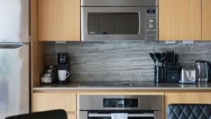 Una cocina moderna con armarios de madera, un microondas de acero inoxidable, una cafetera y un horno.