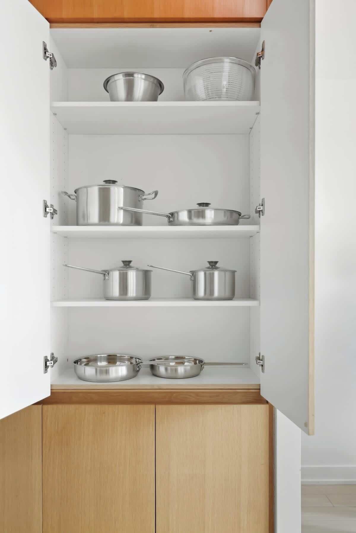 A kitchen cabinet with multiple shelves, each holding various kitchenware items.