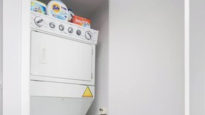 Ein kleiner, weißer Hauswirtschaftsraum mit Waschmaschine und Trockner, die übereinander gestapelt sind.