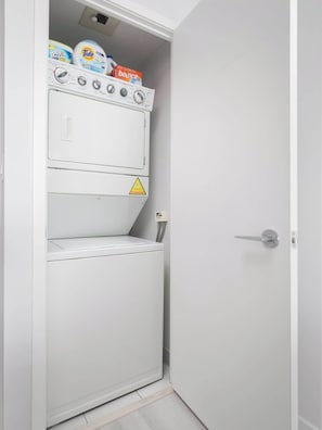 A compact, white laundry room with a washing machine and dryer stacked vertically.