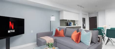 Una sala de estar moderna con un televisor de pantalla plana, sofá gris y una mesa de centro con una planta.