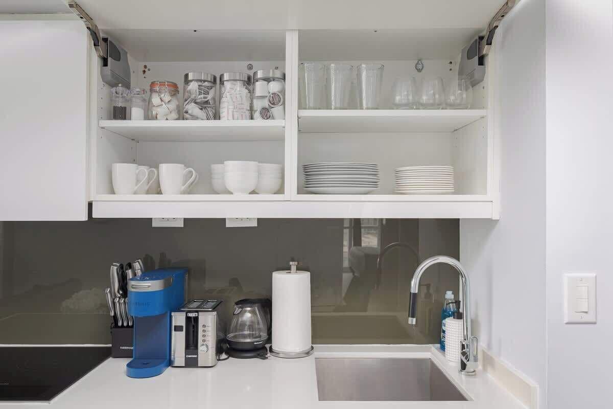A kitchenette with a coffee maker, toaster, kettle, and a sink.