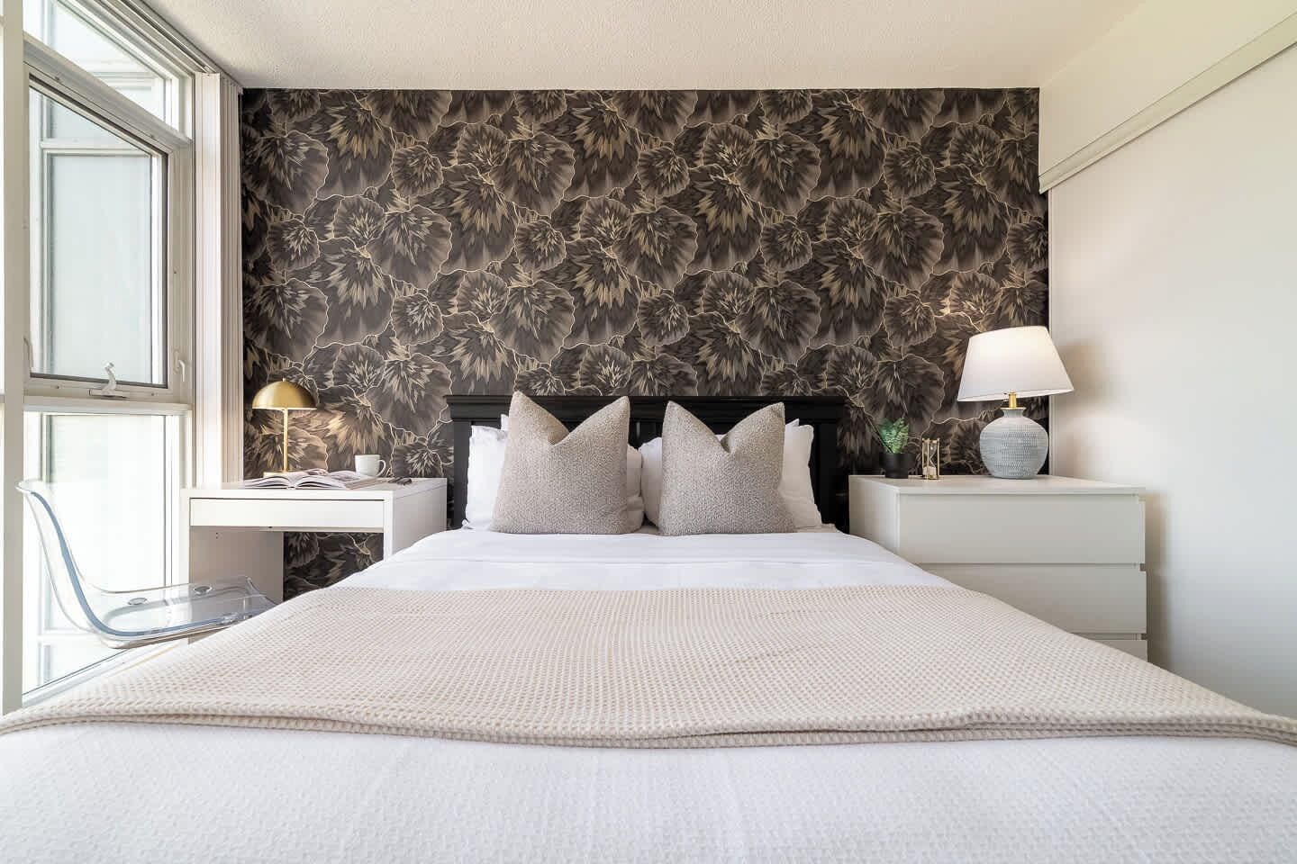 A modern bedroom with a large bed, two bedside tables with lamps, a desk, and a chair.