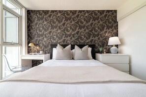 A modern bedroom with a large bed, two bedside tables with lamps, a desk, and a chair. - Modern City Escape 1BR Downtown Toronto (Toronto)