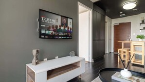 A modern living room with a flat-screen TV mounted on the wall, a white console table, and a black coffee table with a book. - Modern City Escape 1-BR Retreat Downtown Toronto (Toronto)
