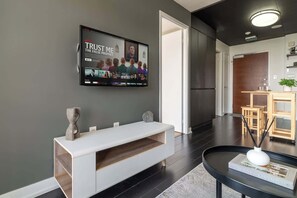 A modern living room with a flat-screen TV mounted on the wall, a white console table, and a black coffee table with a book. - Modern City Escape 1-BR Retreat Downtown Toronto (Toronto)