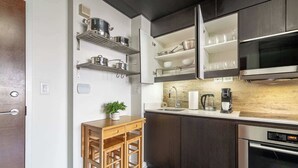 A modern kitchen with dark cabinetry, stainless steel appliances, and open shelving for dishes and cookware. - Modern City Escape 1-BR Retreat Downtown Toronto (Toronto)