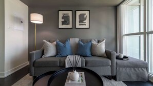 A modern living room with a grey sofa, a round coffee table, and a floor lamp. - Modern City Escape 1-BR Retreat Downtown Toronto (Toronto)