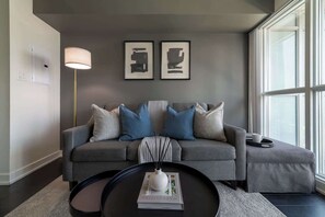 A modern living room with a grey sofa, a round coffee table, and a floor lamp. - Modern City Escape 1-BR Retreat Downtown Toronto (Toronto)