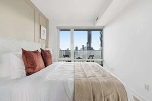 Ein Schlafzimmer mit einem großen Bett, Blick auf die Stadt durch das Fenster und einem modernen Design.