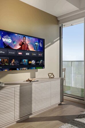 A modern living room with a large flat-screen TV mounted on the wall displaying a streaming service interface.