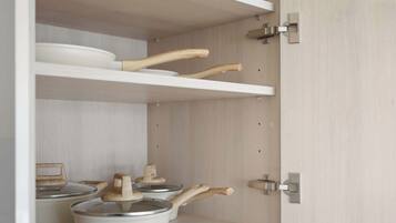 Una cocina con horno microondas integrado, utensilios de madera y una olla sobre la encimera.