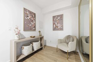 Ein modernes Wohnzimmer mit einer Couch, einem Konsolentisch mit Dekoration und zwei abstrakten Bildern an der Wand.