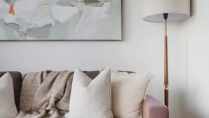 A living room with a sofa, a lamp, and a glass coffee table. - Modern 1BR Suite Steps to Subway City Views! (Toronto)