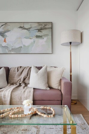 Ein Wohnzimmer mit einer Couch, einer Lampe und einem Glastisch.