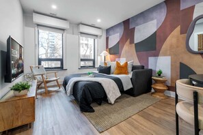 A modern bedroom with a bed, bedside tables, a desk, and a large window. - Downtown 1BR near Elm Street | King Bed | Parking Available (Toronto)