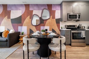 A modern kitchen with stainless steel appliances, a dining area with a round table and chairs, and a geometric wall design. - Downtown 1BR near Elm Street | King Bed | Parking Available (Toronto)