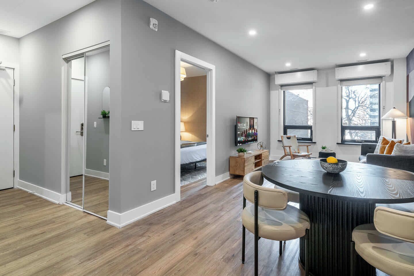 A modern kitchen with a dining area, featuring a round table, chairs, and a TV.