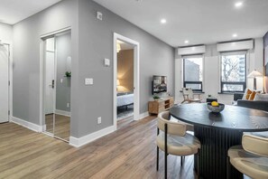 A modern kitchen with a dining area, featuring a round table, chairs, and a TV. - Downtown 1BR near Elm Street | King Bed | Parking Available (Toronto)