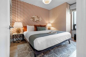 Ein modernes Hotelzimmer mit einem großen Bett, zwei Nachttischen, einer Wand mit Muster und einem Fenster.