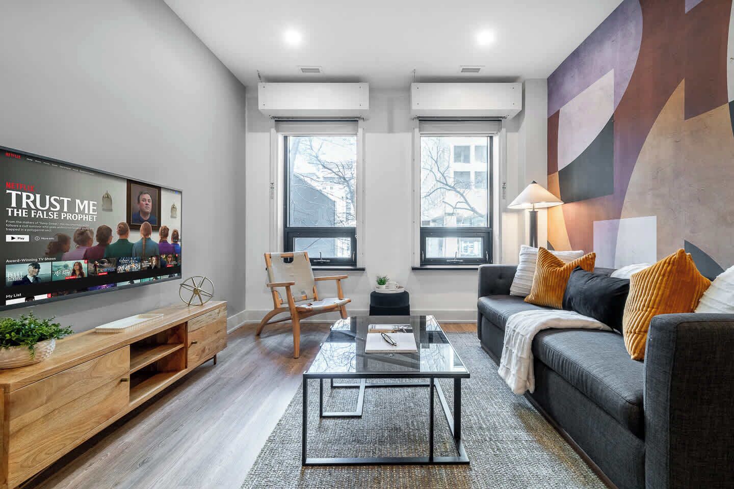 A modern living room with a flat-screen TV, a sofa, a coffee table, and a chair.