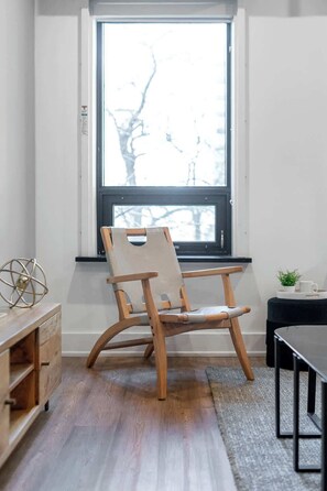 A wooden chair with a cushioned seat and backrest, positioned in front of a window with a view of bare trees. - Downtown 1BR near Elm Street | King Bed | Parking Available (Toronto)
