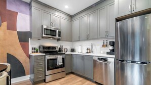 Una cocina moderna con electrodomésticos de acero inoxidable, armarios grises y piso de madera.
