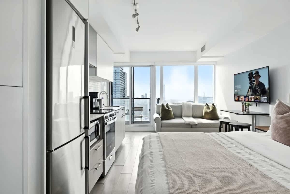 Une chambre d’hôtel moderne équipée d’une kitchenette, d’un grand lit, d’un canapé et d’une télévision.
