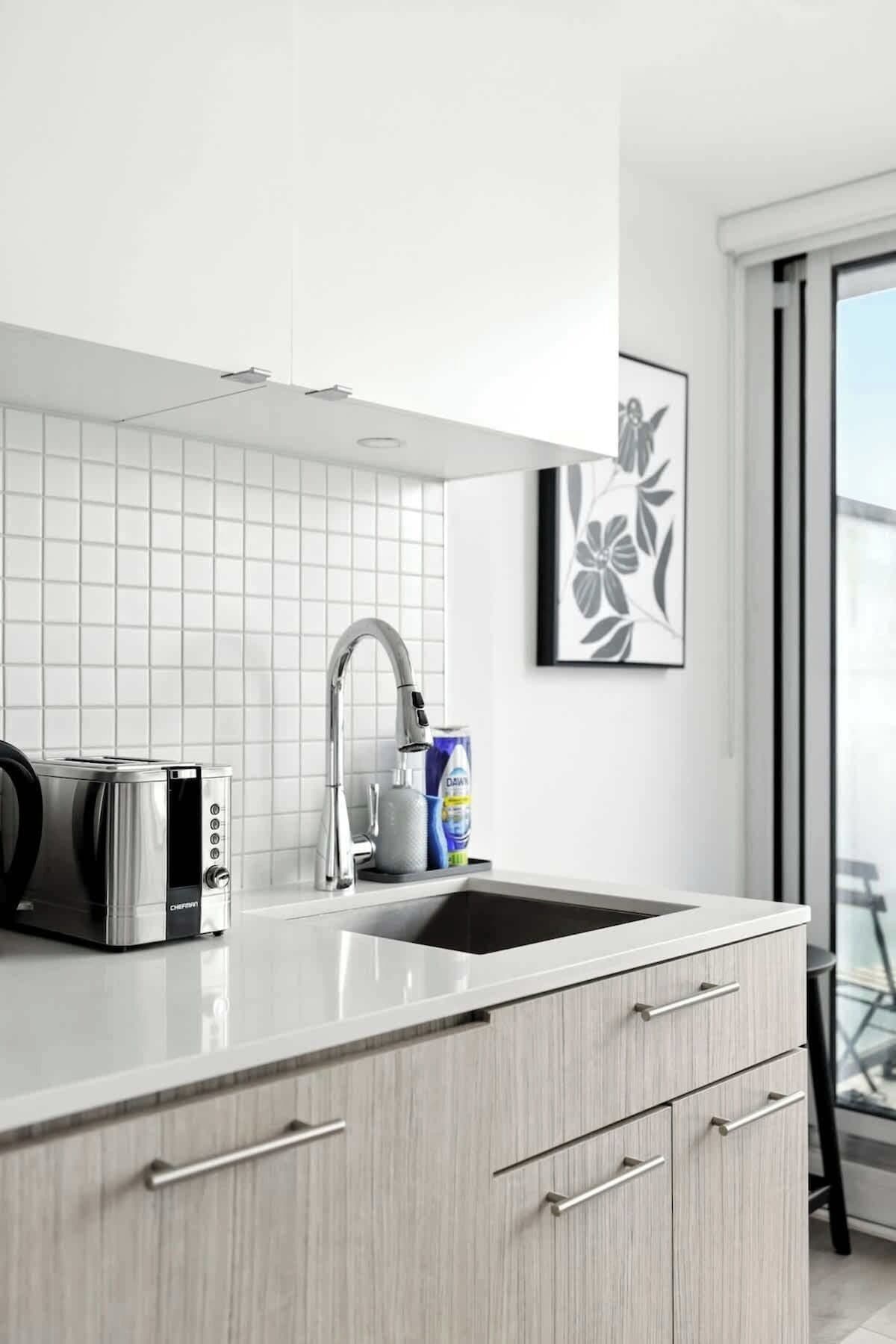 A modern kitchen with a built-in toaster, a stainless steel faucet, and a large window.
