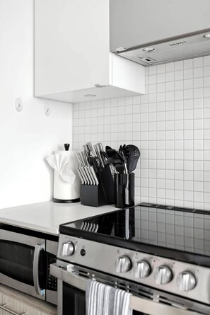 A modern kitchen with a stainless steel stove, oven, and microwave. - Sleek studio near Eaton Centre in central downtown (Toronto)