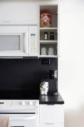 A compact kitchen with a microwave, coffee maker, and a kettle on the countertop. - Stylish 1BR Lakeside Oasis Patio & Prime Location | Parking Available (Toronto)