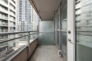 A narrow balcony with a glass door, a metal railing, and a view of adjacent high-rise buildings. - Stylish 1BR Lakeside Oasis Patio & Prime Location | Parking Available (Toronto)