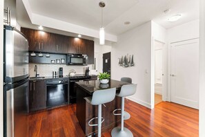 Una cocina moderna con armarios de madera oscura, electrodomésticos de acero inoxidable y una isla central con taburetes de bar.
