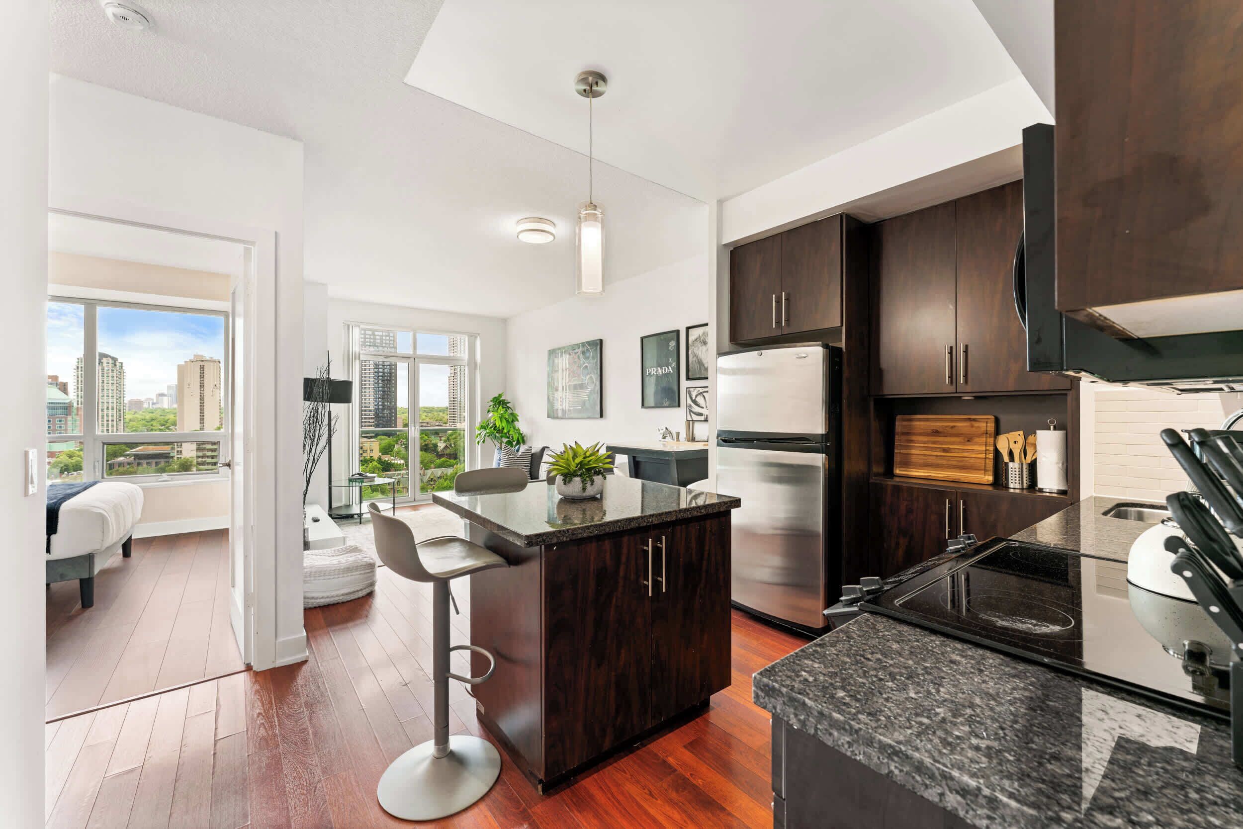 A modern kitchen with dark wood cabinets, stainless steel appliances, and a bar stool.