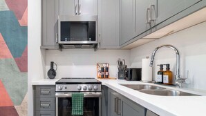 Uma cozinha equipada com micro-ondas, fogão, forno e pia.