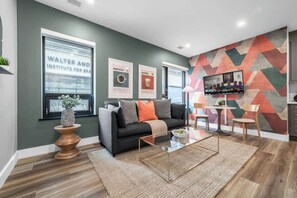 A modern living room with a sofa, coffee table, and a TV mounted on the wall. - Serene Downtown Stay, steps to Mount Sinai | Parking Available (Toronto)
