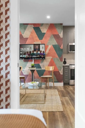 A modern kitchen with a geometric patterned wall, a flat-screen TV mounted above a dining table, and contemporary cabinetry. - Serene Downtown Stay, steps to Mount Sinai | Parking Available (Toronto)