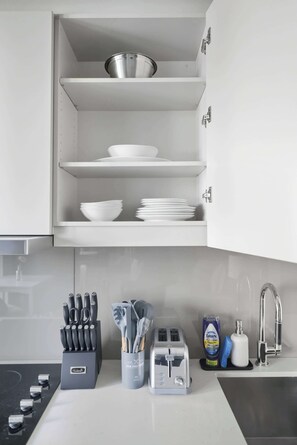 A kitchen with white cabinets, a stainless steel sink, and a toaster on the counter.