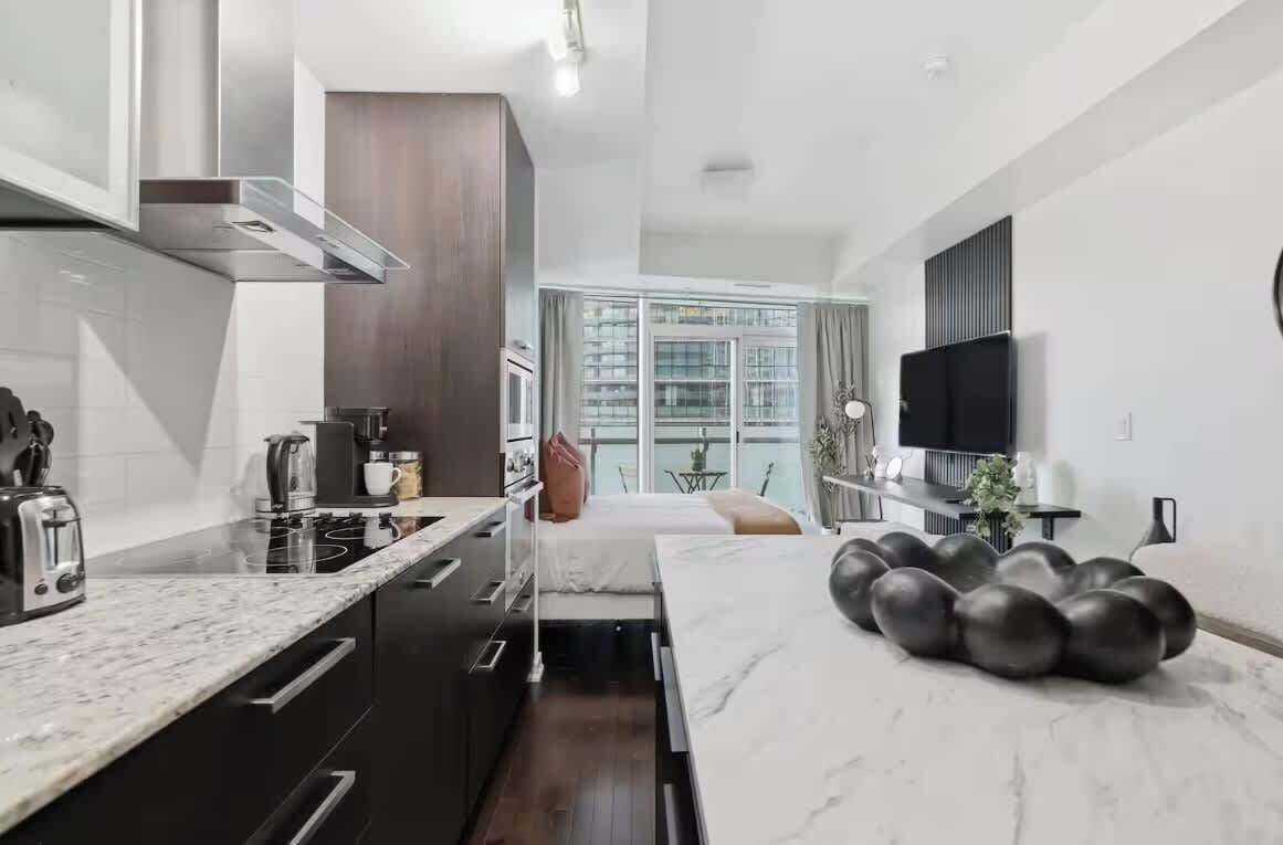 A modern kitchen with a built-in stove, a dining area with a marble countertop, and a living space with a flat-screen TV.