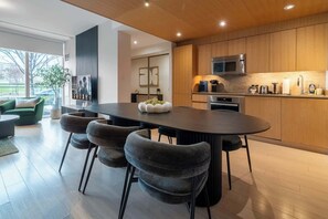 A modern kitchen with a central island, wooden cabinets, and a dining area with a round table and chairs. - Private Home, 3 BR, Rogers Centre & Free Parking (Toronto)