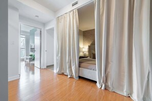 A modern bedroom with a bed, curtains, and a nightstand. - Private Home, 3 BR, Rogers Centre & Free Parking (Toronto)
